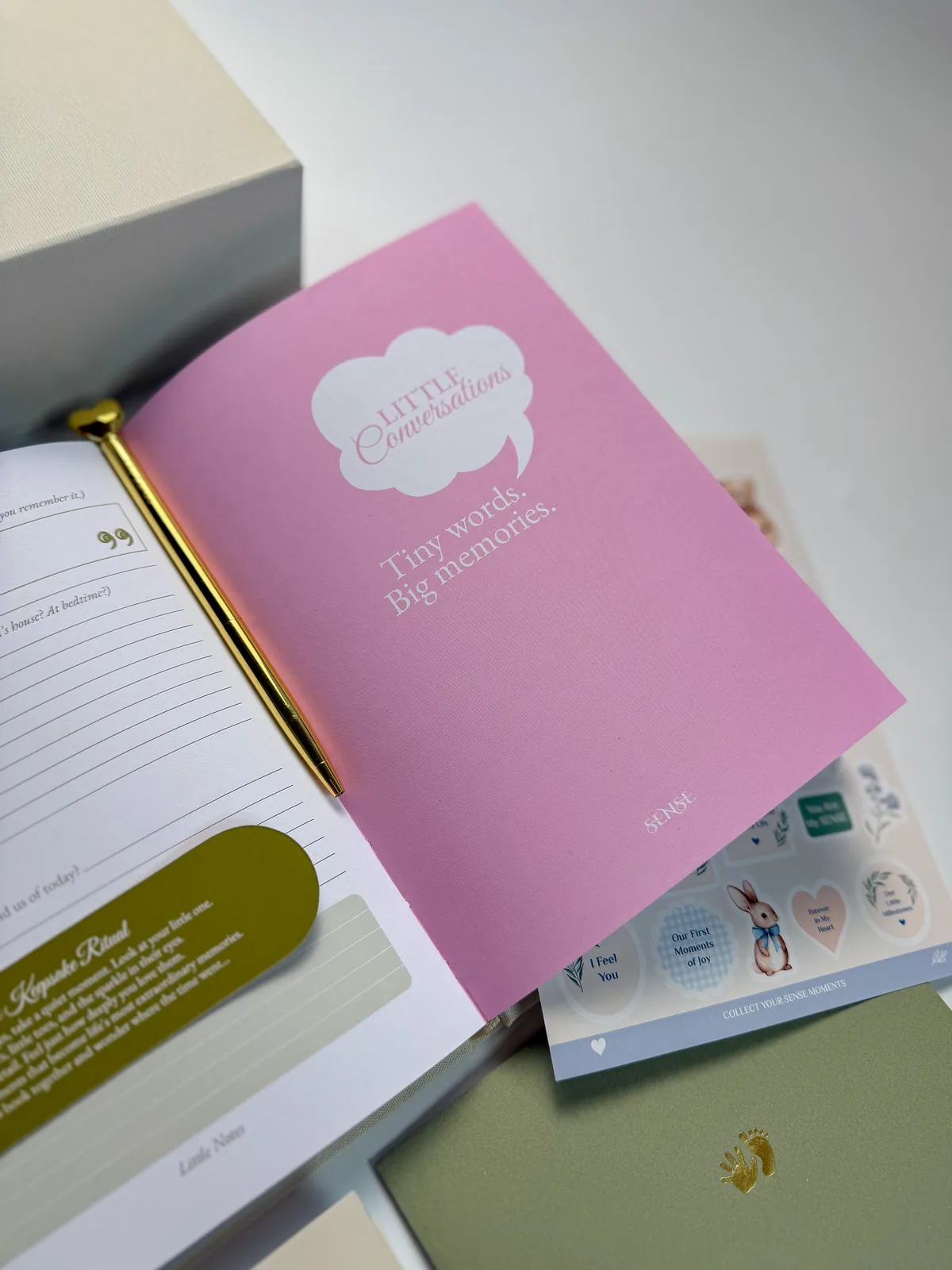 English-edition baby memory book with the Little Conversations booklet beside the cream box