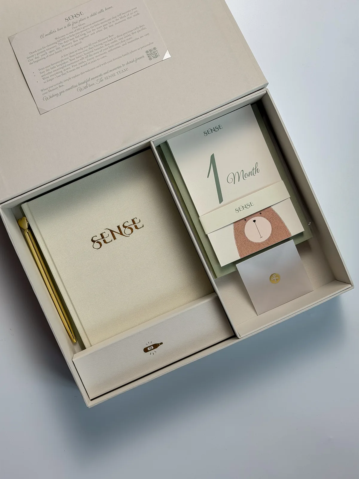 Open cream SENSE baby memory box with the English-edition book and a month card