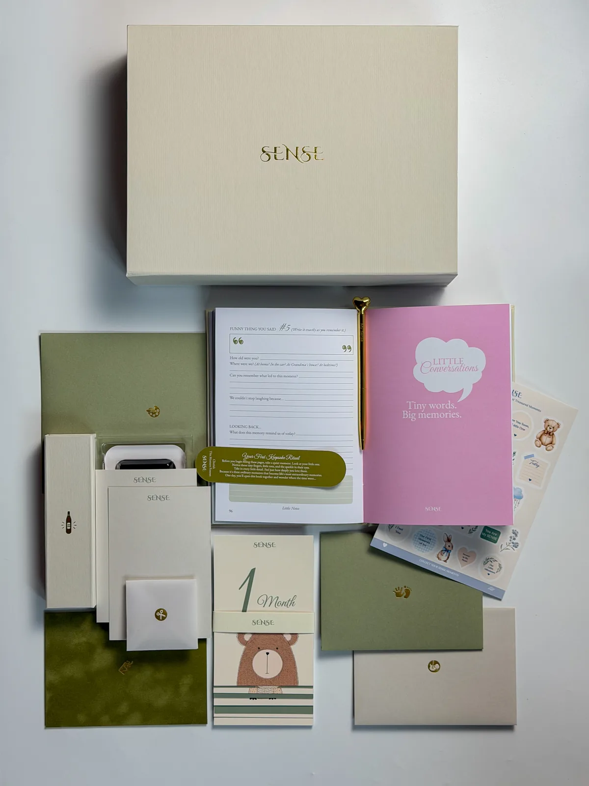 Cream SENSE baby memory box with the full contents of the English edition laid out beside it