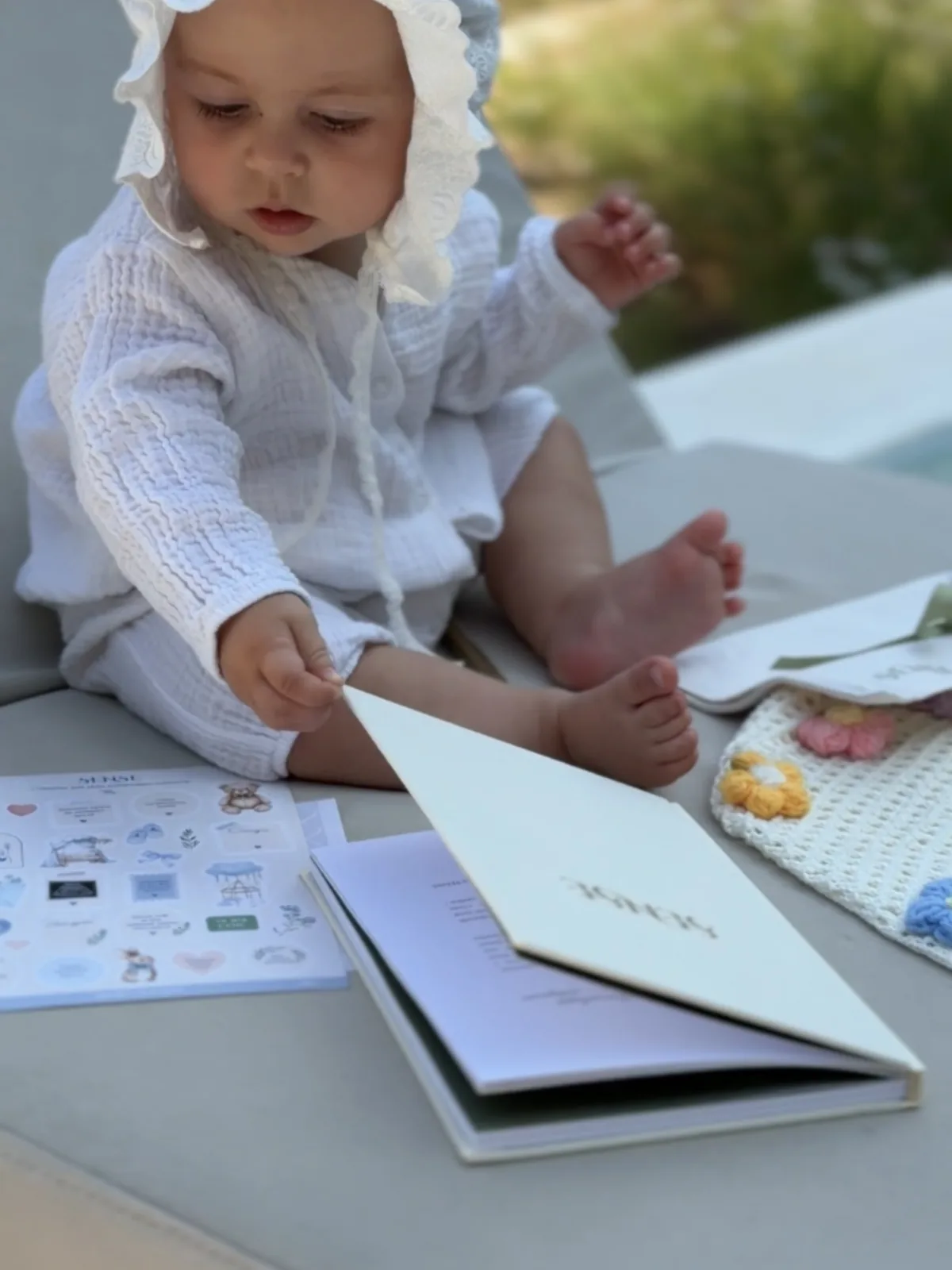 A baby leafing through the cream SENSE baby memory book